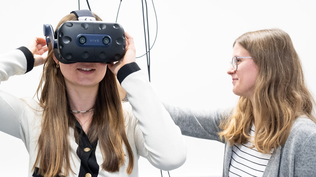 Bild in Originalgröße ansehen Hannah Großwieser (l.) und Katharina Stiller (r.) demonstrieren die Virtualisierung des realen Versuchs in Ulm per VR-Brille. (Foto: Peter Thomas)
