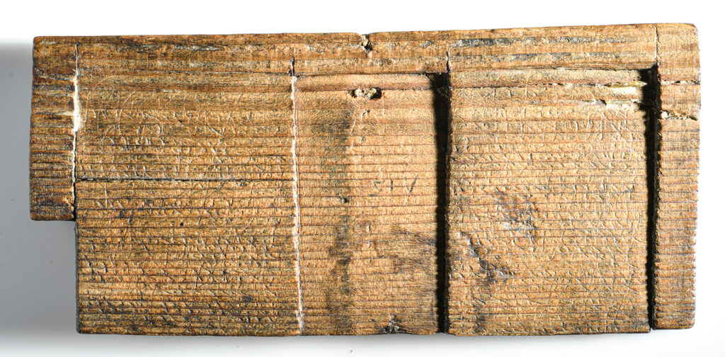 Von beiden Text-Phasen auf der Vorderseite und der hier abgebildeten Rückseite des Schreibtäfelchens sind nur Ausschnitte erhalten, soweit sich eben die Spitze des eisernen Griffels – stilus – durch die Wachsschicht ins Holz durchgedrückt hatte. Der ältere Text erwähnt lictores, also Leibgarden und Amtsdiener. Im jüngeren Text geht es um einen Rechtsakt, vermutlich um die Entfernung bestimmter Siegel. (© Gallo-Romeins Museum Tongeren-Borgloon)
